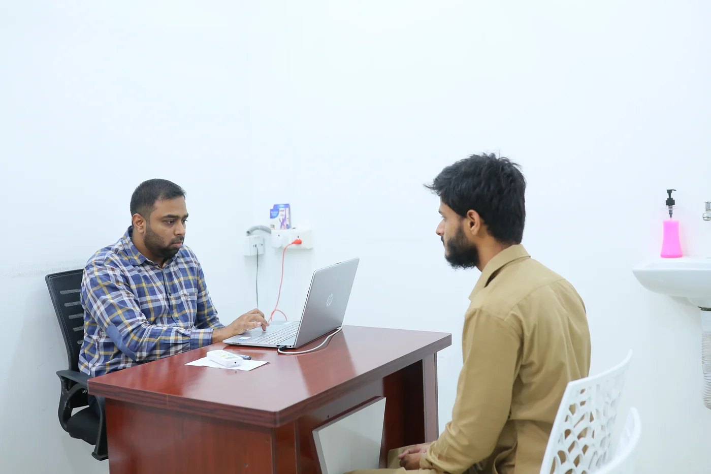 Dr Abdullah Kamlur across his desk in the psychiatry consulting room at Caspian Healthcare, Vijay Nagar Colony, Hyderabad