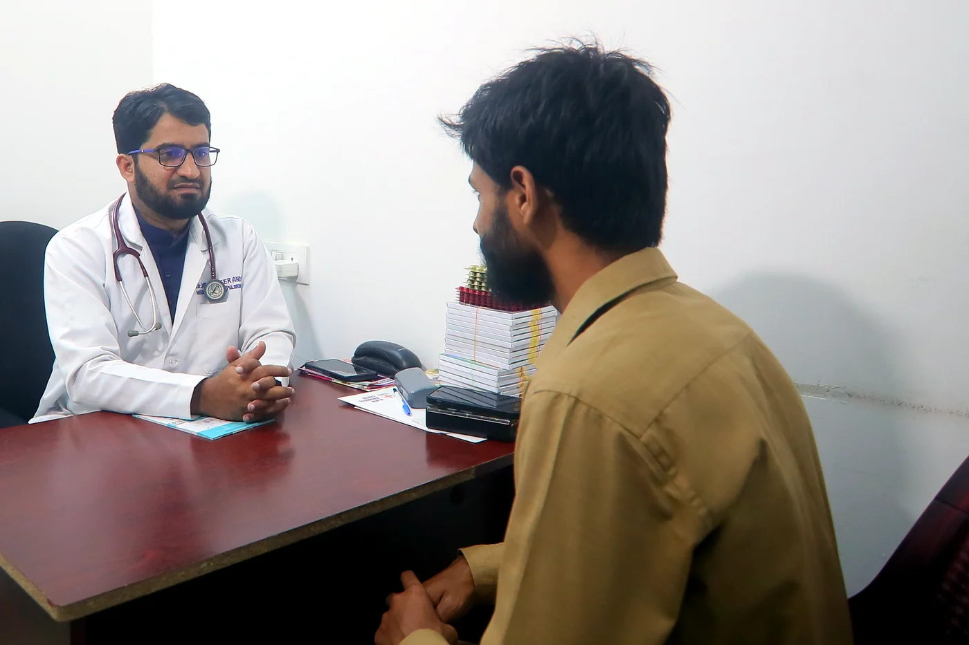 Dr Mohammad Sameer Ahmed in consultation across his desk in the outpatient room at Caspian Healthcare, Vijay Nagar Colony, Hyderabad